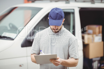 Delivery man writing on clipboard