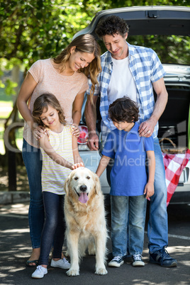Smiling family standing in front of a car