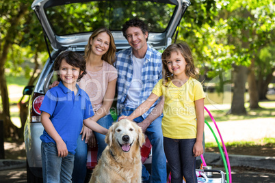 Smiling family in front of a car