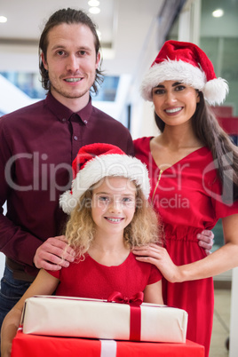 Family in Christmas attire standing with Christmas gifts