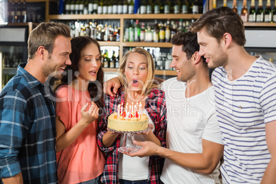 Woman blowing out candles while friends watch