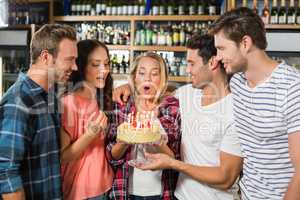 Woman blowing out candles while friends watch
