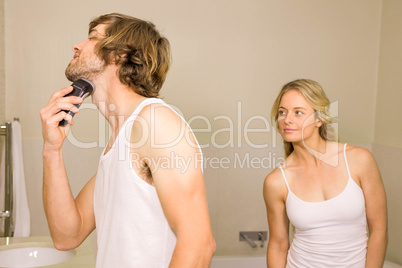 Handsome man about to shave with his girlfriend behind