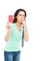 Mature woman blowing whistle and holding red card