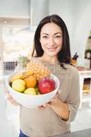 Portrait of smiling woman holding fruits bowl