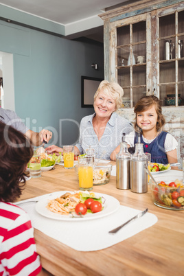 Portrait of smiling granny and granddaughter sitting at dining t