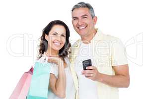 Happy couple holding shopping bags and smartphone