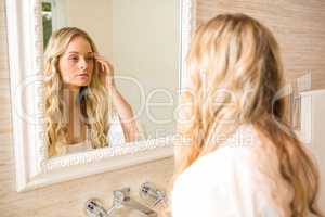 Beautiful blonde looking at herself in the bathroom mirror