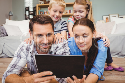 Parents holding digital tablet while kids sitting on their back