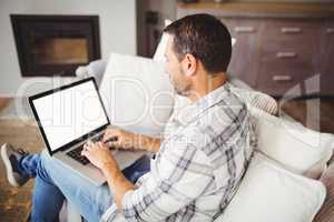 Man working on laptop while sitting on sofa