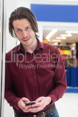 Portrait of man using a mobile phone outside a shop