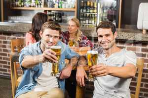 Men toasting in front while women talk behind