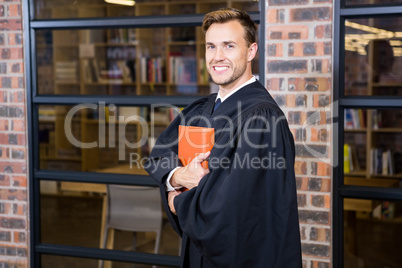 Lawyer standing near library with law book