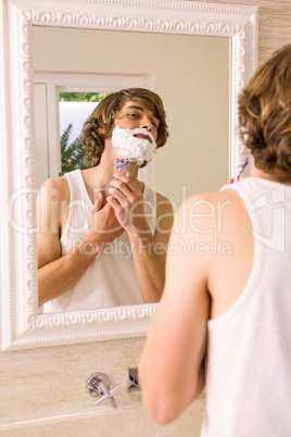 Handsome man shaving in the bathroom