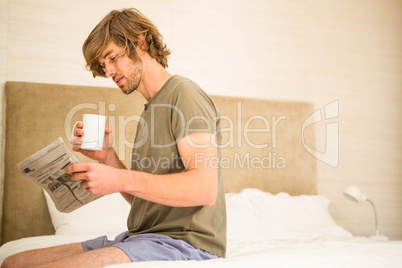 Handsome man reading the news and drinking coffee