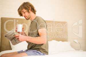 Handsome man reading the news and drinking coffee