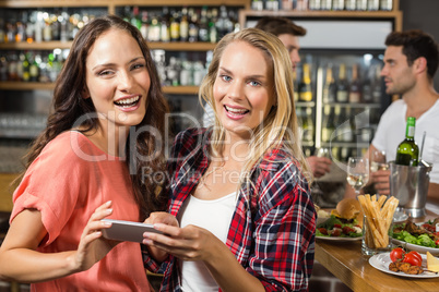 Women looking at camera with phone in hand