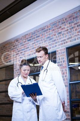 Two doctors looking at clipboard and discussing near library