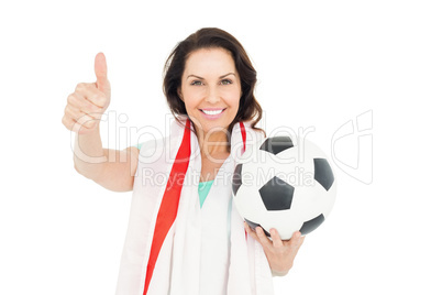 Pretty brunette with thumbs up holding soccer ball