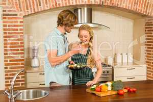 Handsome man making his girlfriend taste the preparation