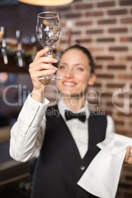 Barmaid looking at a wine glass