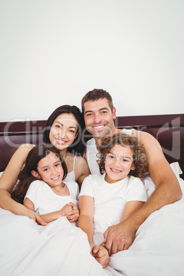 Happy family lying on bed against wall at home