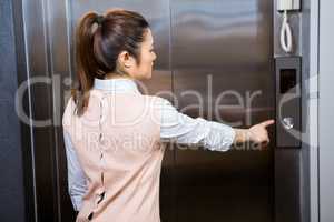 Businesswoman pressing elevator button