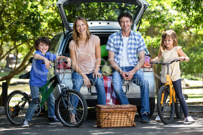 Smiling family in front of a car