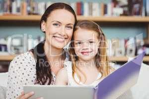 Close-up portrait of mother and daughter with book