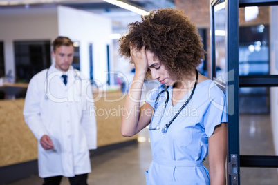 Tensed female doctor standing in hospital