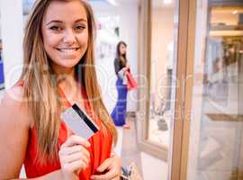 Portrait of happy woman showing her credit card outside a shop