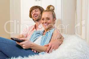 Cute couple watching tv and using remote on the couch