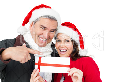 Festive couple pointing christmas gift