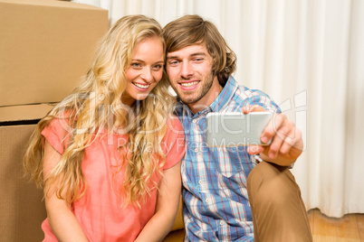 Happy couple sitting on the floor taking selfie