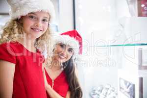 Mother and daughter in Christmas attire smiling in a shop