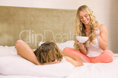 Cute couple eating cereals and lying in bed