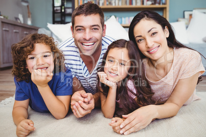 Portrait of cheerful family lying on carpet