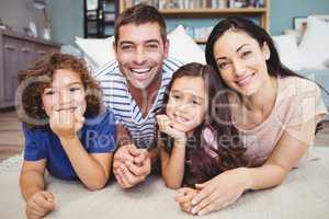 Portrait of cheerful family lying on carpet