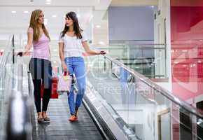 Two beautiful women on escalator of shopping mall