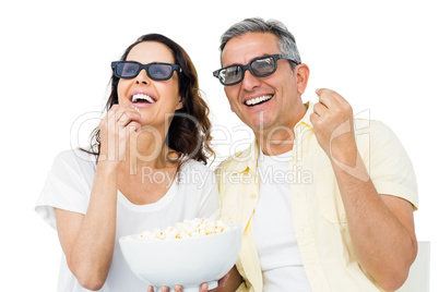 Smiling couple with 3D glasses eating popcorn