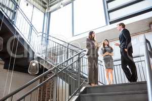 Three executives standing on a staircase