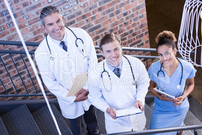 Portrait of doctors standing on staircase with document
