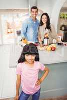 Portrait of smiling girl with parents preparing fruit milkshake