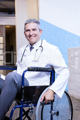 Happy male doctor sitting on wheel chair