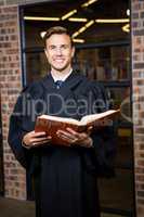 Lawyer standing near library with law book