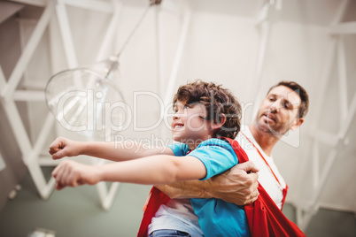 Low angle view of father holding cheerful son wearing superhero