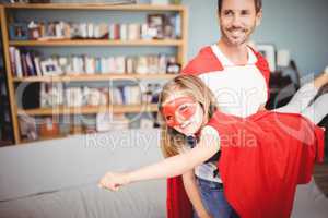Smiling father holding daughter wearing superhero costume