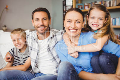 Happy family sitting on sofa against shelf