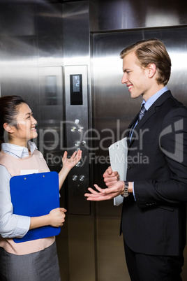 Businessman and businesswoman standing in an elevator