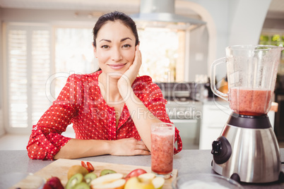 Portrait of smiling woman with fruit juice on table